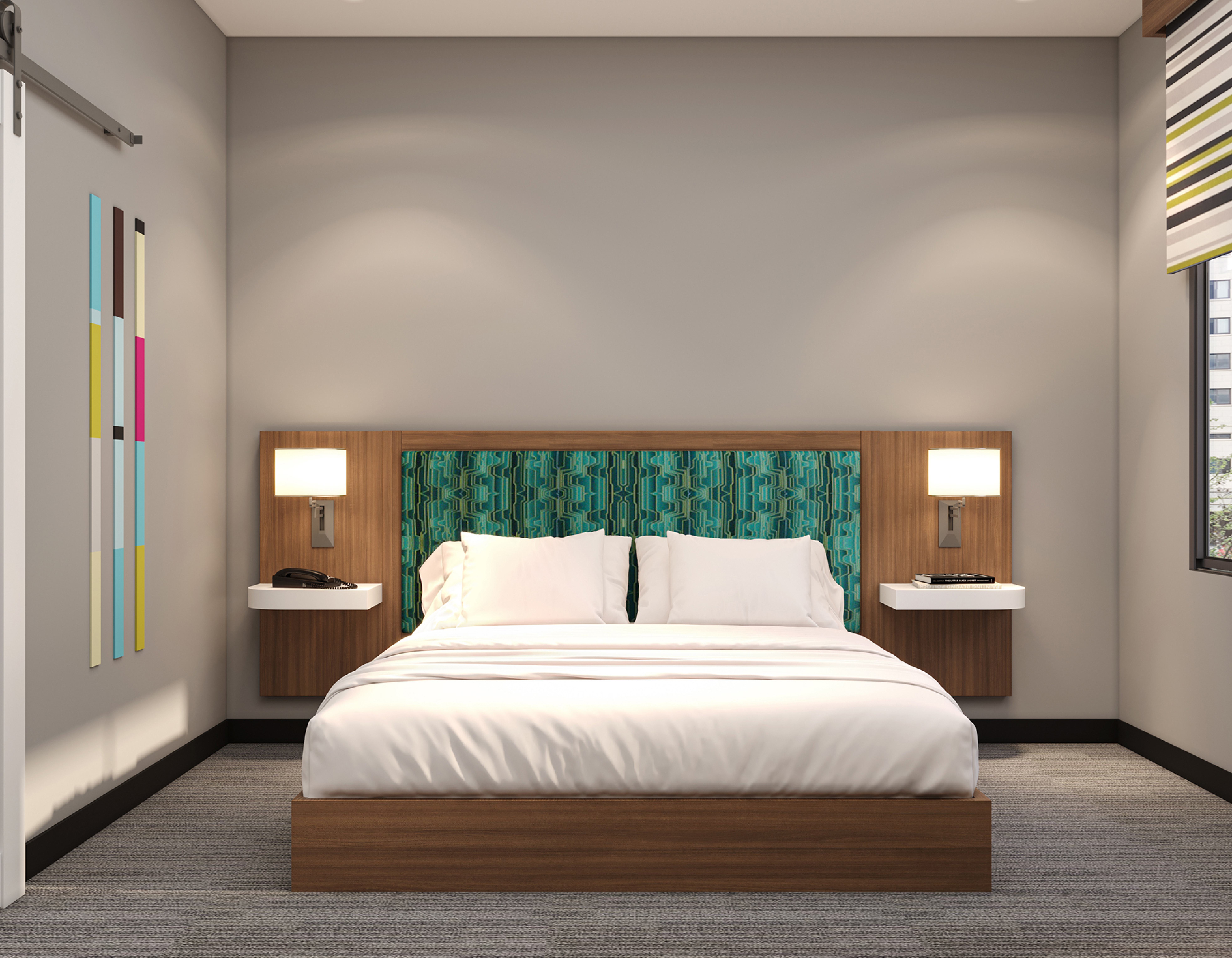 Guest room king bed with teal patterned headboard and wall sconces